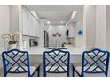 Modern kitchen features white cabinetry, stainless steel appliances, and a breakfast bar with stylish blue chairs at 4947 Green Dolphin Way, Kiawah Island, SC 29455