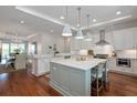 Open-concept kitchen featuring white cabinets, a large island with seating, stainless steel appliances and wood floors at 155 Wingo Way # 415, Mount Pleasant, SC 29464