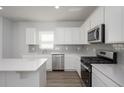 Modern kitchen with white cabinets, gray backsplash, stainless steel appliances, and a center island at 202 W Bradford Pointe Drive Dr, Summerville, SC 29483