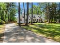Charming white home with shuttered windows is complemented by a paved driveway and lush lawn at 309 Huntington Rd, Summerville, SC 29483