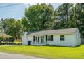 Charming one-story home featuring a white brick exterior, manicured lawn, and a quaint front porch at 407 Tammie Ave, Goose Creek, SC 29445