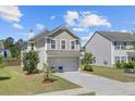 Side view of a home with a two-car garage, lawn, and lush landscaping at 409 Thoroughbred Dr, Moncks Corner, SC 29461