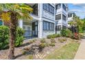 Well-maintained condo building featuring balconies and a lush, landscaped yard with palm trees at 1025 Riverland Woods Pl # 1008, Charleston, SC 29412