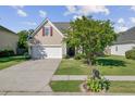 Charming two-story home with a well-maintained lawn, a mature tree, and a driveway leading to the garage at 1034 Sterling Ln, Summerville, SC 29483