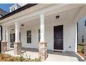 Inviting front porch with brick-based columns and a welcome mat at the entrance of home 119 at 119 Summer Tanager Dr, Ravenel, SC 29470