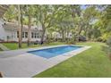 Inviting pool with a sleek patio, surrounded by towering palm trees and well-maintained grassy area at 126 Sparrow Dr, Isle of Palms, SC 29451