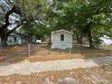 Street view of a single-wide mobile home featuring mature trees and a chain link fence at 5626 Shelton St, North Charleston, SC 29406