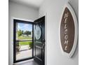 Inviting entryway with a surfboard welcome sign, and a black front door open to an outdoor view at 655 Jancus St, Charleston, SC 29414