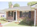 Quaint brick home featuring black shutters, fresh landscaping, and a welcoming front entrance at 7712 Corley Dr, North Charleston, SC 29418