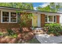Inviting brick home with a yellow door, complemented by well-maintained landscaping and classic architectural details at 1172 Dawn Dr, Charleston, SC 29412