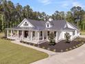 A gorgeous home with a spacious front porch, featuring rocking chairs, swings, and beautiful landscaping at 1245 Saddlehorn Rd, Summerville, SC 29486