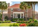 A brick home with a red roof features elegant staircases, palm trees, and manicured landscaping for curb appeal at 13 Broughton Rd, Charleston, SC 29407