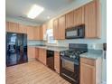 Well-lit kitchen featuring wooden cabinets, black appliances, and laminate flooring at 132 Lynches River Dr, Summerville, SC 29485