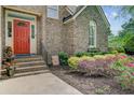 Inviting red front door with brick steps and lush landscaping, creating a warm and welcoming entrance at 1391 Southlake Dr, Mount Pleasant, SC 29464