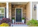 Charming front entrance with stone accents, decorative wreath, manicured plants, and welcoming door mat at 1606 Stovall Ct, Johns Island, SC 29455