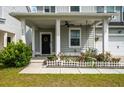 Inviting covered porch with white columns, fan, porch swing, and blooming flowers in front of the home at 206 Evergreen Ave, Summerville, SC 29485
