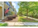 Row of townhomes with manicured lawns and patriotic decor under a partly cloudy sky at 2096 Promenade Ct, Mount Pleasant, SC 29466