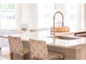 Elegant kitchen island featuring a stainless steel sink and gooseneck faucet, with seating and woven chairs at 224 Callibluff Dr, Summerville, SC 29486