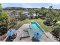 Aerial view of a modern pool with a hot tub, striped umbrellas, and waterfront views at 2254 Beckenham Dr, Mount Pleasant, SC 29466