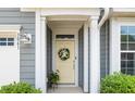 Inviting entryway featuring a decorative wreath on a cream-colored door with sidelights and potted plants at 3061 Cross Vine Ln, Summerville, SC 29483