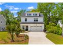 Charming two-story home with black roof, white siding, two car garage, and a well manicured front yard at 481 Woodland Shores Rd, Charleston, SC 29412