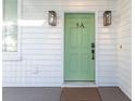 Close-up of a charming light green front door with modern black hardware and stylish exterior lighting at 5 Addison St, Charleston, SC 29403