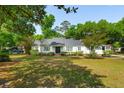 Beautiful white home with a black roof, surrounded by mature trees and green lawn at 667 Shortwood St, Charleston, SC 29412