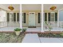 Inviting front porch with white pillars, a light green door, and flower baskets creating a warm entrance at 1429 Swamp Fox Ln, Charleston, SC 29412