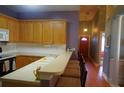 Kitchen with wooden cabinets, breakfast bar with seating, and hardwood floors leading to a hallway at 1757 Wayah Dr, Charleston, SC 29414