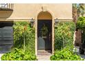 An inviting front entrance with lush greenery, a wreath, elegant sconces, and a black door at 24 Archdale St, Charleston, SC 29401