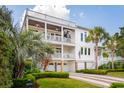 Beautiful three-story home with multiple balconies, a spiral staircase, palm trees, and a lush green lawn at 3 37Th Ave, Isle of Palms, SC 29451