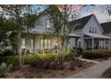 Cozy two-story home with a front porch featuring seating amidst a meticulously landscaped front yard at 308 Scholar Way, Summerville, SC 29486