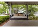 Relaxing porch swing complete with pillows on a stained wood porch floor at 308 Scholar Way, Summerville, SC 29486