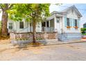 Charming exterior featuring white siding, light blue shutters and a brick wall around the raised front yard at 4 Addison St, Charleston, SC 29403
