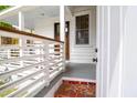 Inviting front porch featuring white railings, a stained wood door and a brick landing at 4 Addison St, Charleston, SC 29403