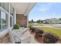 Inviting front porch with white wicker chairs, stone accents, and a view of the landscaped neighborhood street at 440 Four Seasons Blvd, Summerville, SC 29486