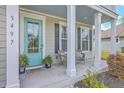 Charming front porch with inviting seating and a pop of color with a turquoise door at 5497 Alpine Dr, Summerville, SC 29483