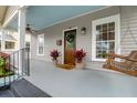 Inviting front porch with a swing, dark wood door with wreath, and potted plants at 71 Cypress St, Charleston, SC 29403