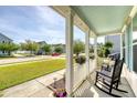 Relaxing front porch view showcasing a charming neighborhood street, complete with rocking chairs and blooming flower boxes at 7414 Purser Ln, Hanahan, SC 29410