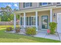 Charming front entrance with well-manicured landscaping, a security system sign, and green shutters at 7477 Painted Bunting Way, Hanahan, SC 29410
