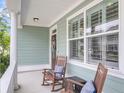 Relaxing front porch featuring rocking chairs, white columns, and charming exterior details at 81 Crossandra Ave, Summerville, SC 29483