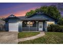 Charming blue home with a white porch, green lawn, and attached garage at sunset at 8268 Timberidge Ct, North Charleston, SC 29420