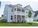 Beautiful two-story home featuring a cozy front porch with hanging flowers and a well-manicured lawn at 1100 Saltwater Cir, Johns Island, SC 29455
