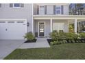 Inviting front porch with a decorative wreath, potted flowers, and a freshly manicured lawn at 1166 Turkey Trot Dr, Johns Island, SC 29455