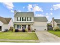 Attractive two-story house featuring a quaint front porch, attached garage, and lovely lawn with flowerbeds at 137 Cotillion Cres, Summerville, SC 29483