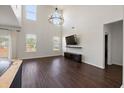 Spacious living room boasts soaring ceilings, large windows, modern chandelier, dark wood floors and media center at 144 Marinella Dr, Goose Creek, SC 29445