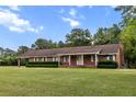 Well-maintained brick home featuring a covered carport and lush lawn at 228 Dogwood Trl, Harleyville, SC 29448