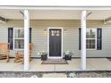 Inviting front porch with decorative plants, rocking chairs and a modern front door at 255 S Railroad Ave, Ridgeville, SC 29472