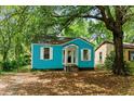 Exterior view of quaint blue home featuring a well-manicured lawn and lush, mature trees at 2654 Harvey Ave, North Charleston, SC 29405