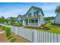 Charming two-story home with a white picket fence, manicured landscaping, and light teal siding at 3941 Bessemer Rd, Mount Pleasant, SC 29466